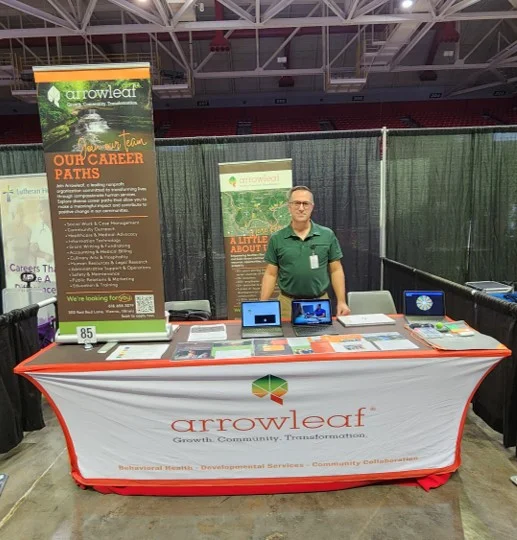 An Arrowleaf team member stands at an Arrowleaf booth at a conference.