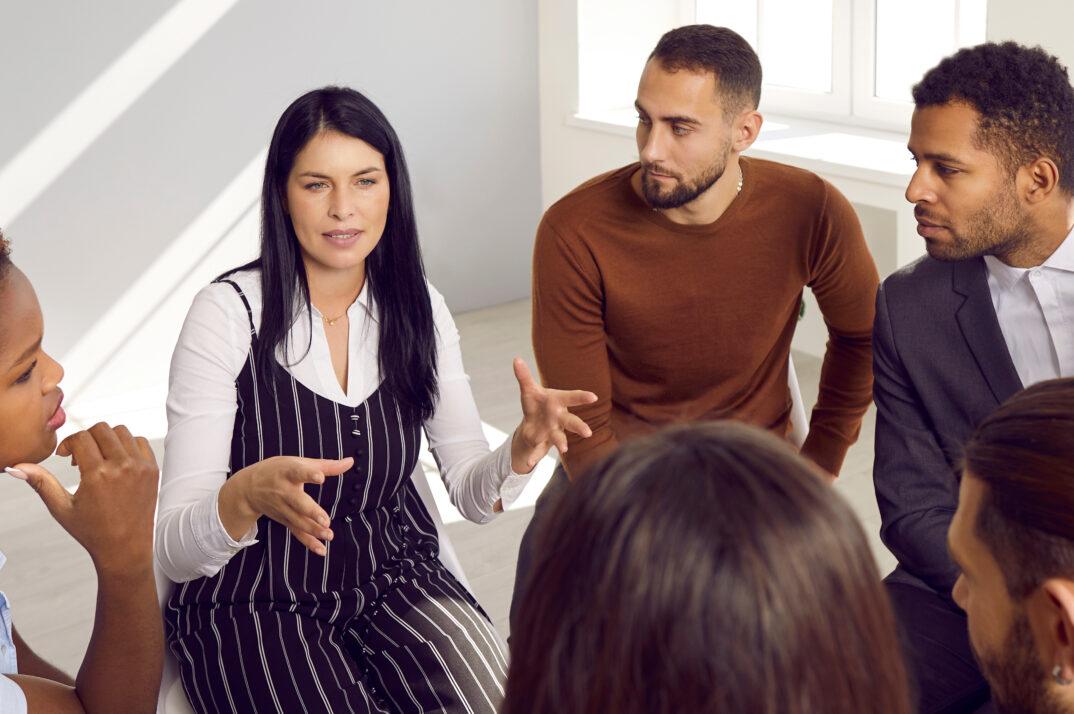 A group of colleagues sit in a circle and discuss.