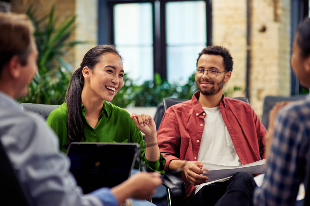A woman discusses a project with colleagues as they all smile.