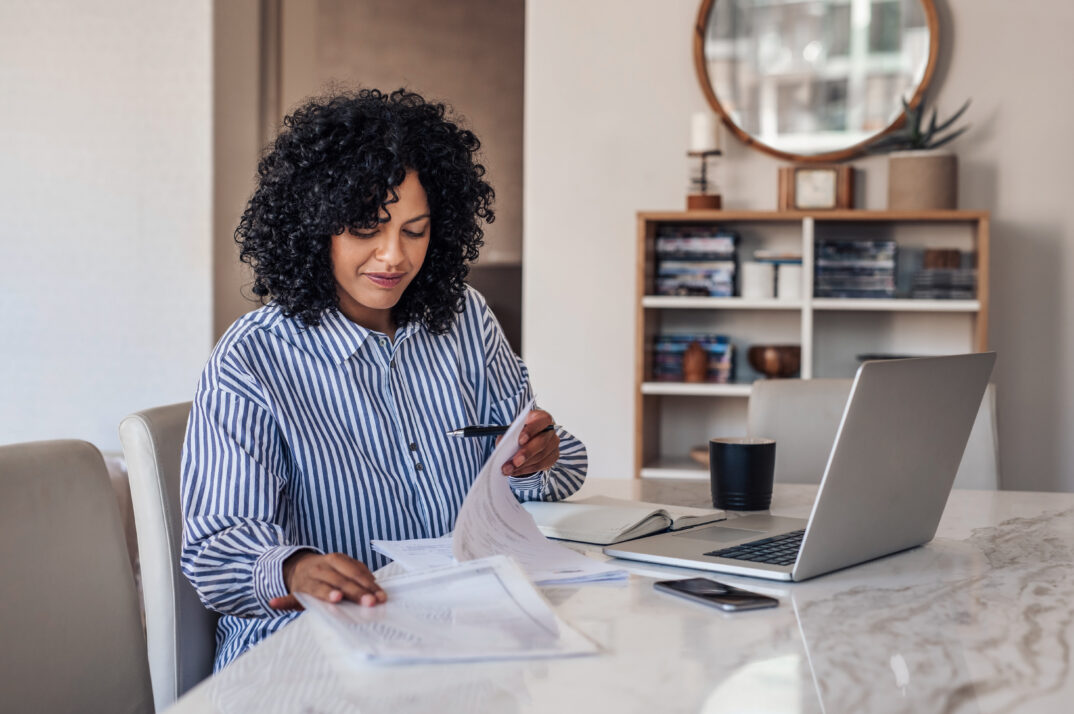A woman sorts papers at a table.