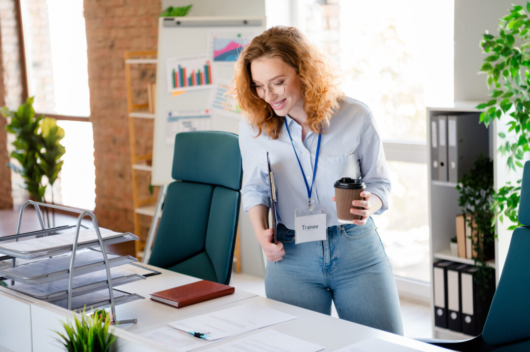 Photo of a trainee arriving at her desk and smiling.
