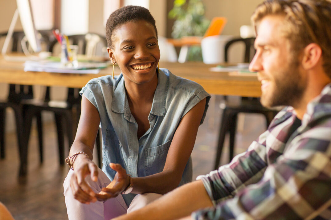 Two people have a conversation while smiling at one another.
