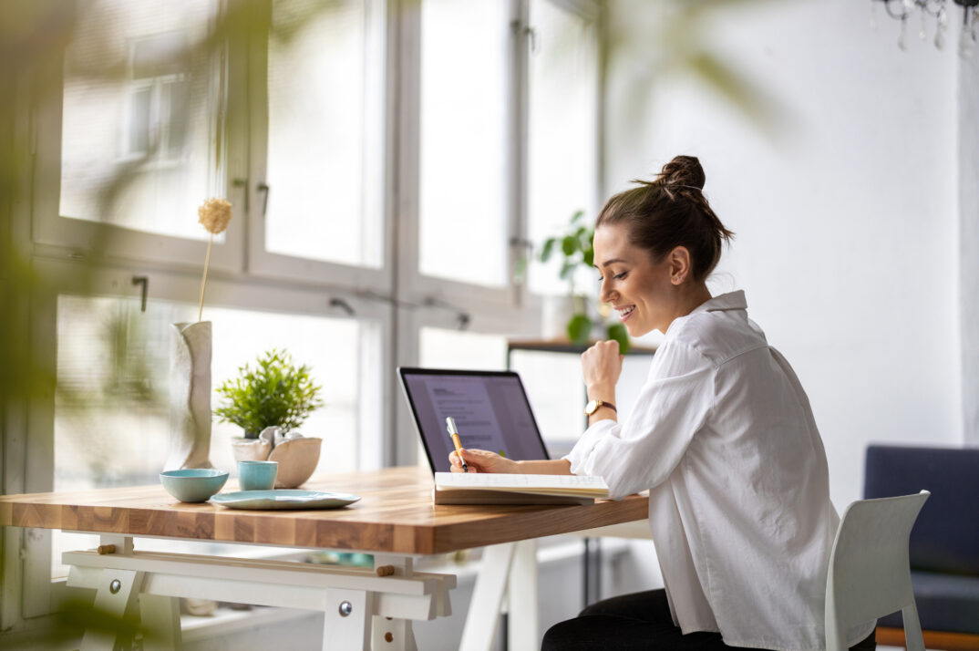 A woman works at a desk near a window.