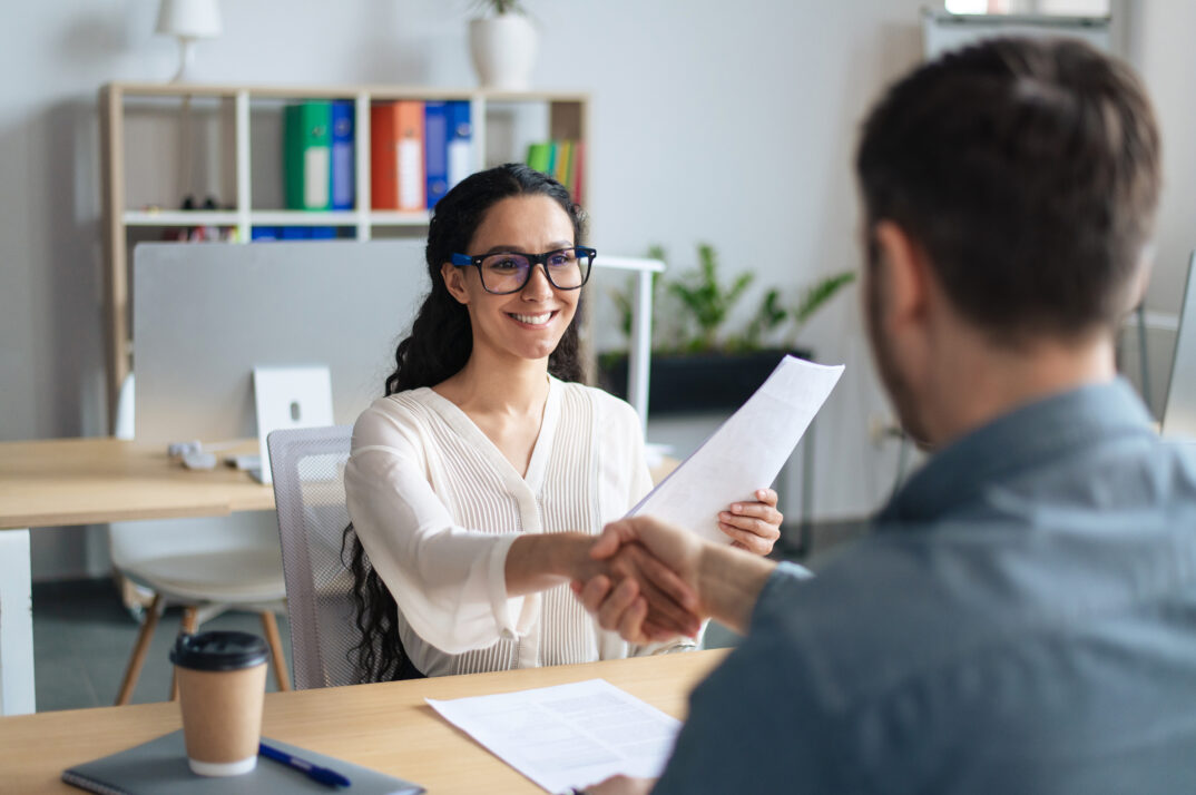 Two people shake hands at the end of a job interview.